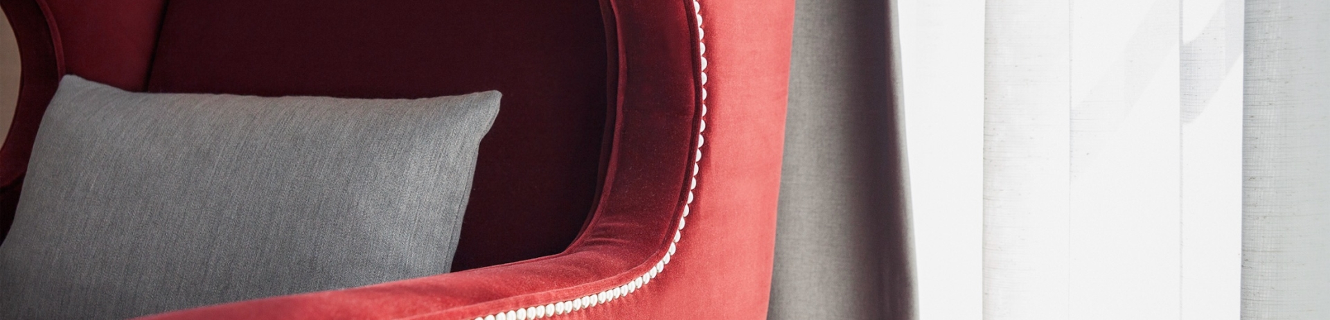 A red wingback armchair with a grey throw pillow