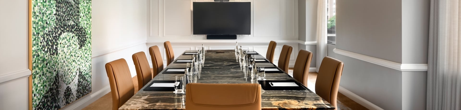 A conference room with a long table and leather chairs.