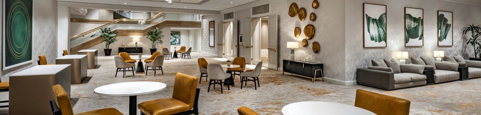 A large hotel venue with tables, chairs and sofas.
