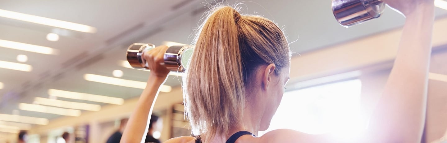 woman lifting two dumbbells in the gym