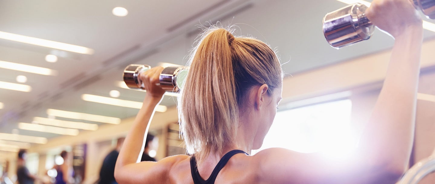 woman lifting two dumbbells in the gym