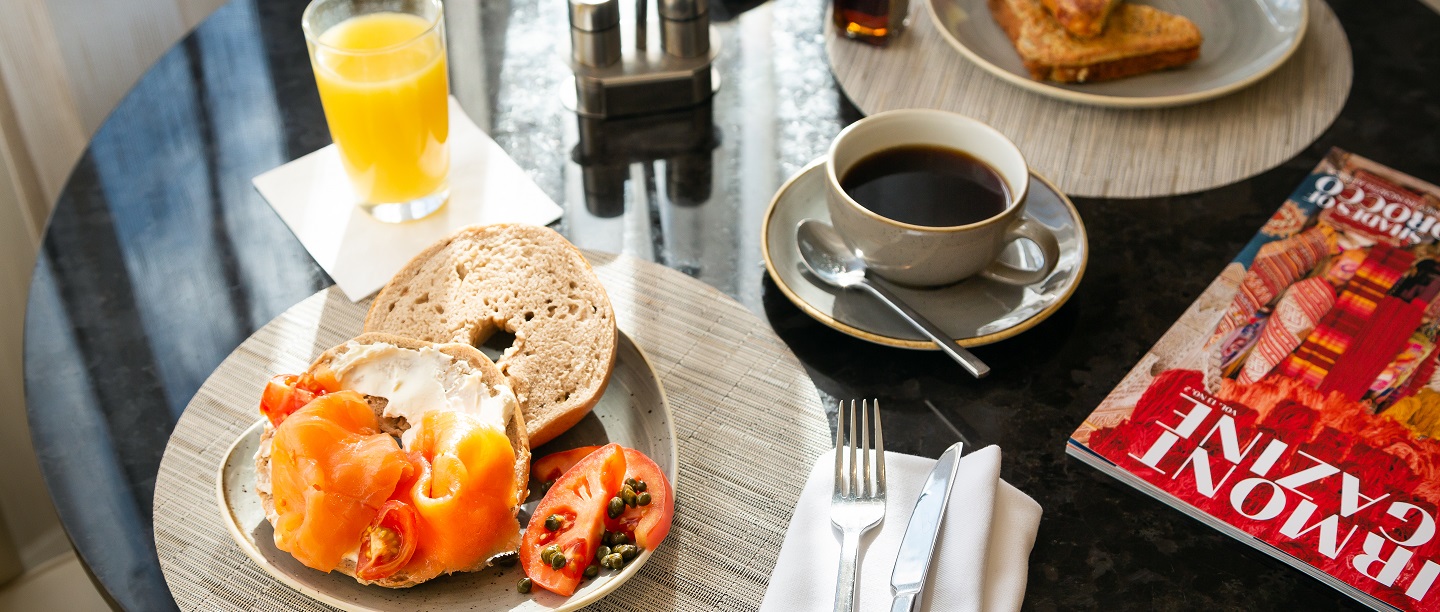bagel with cream cheese and salmon on a plate next to a cup of coffee