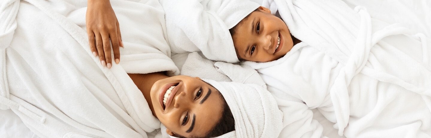 woman and child in bathrobes laying beside each other