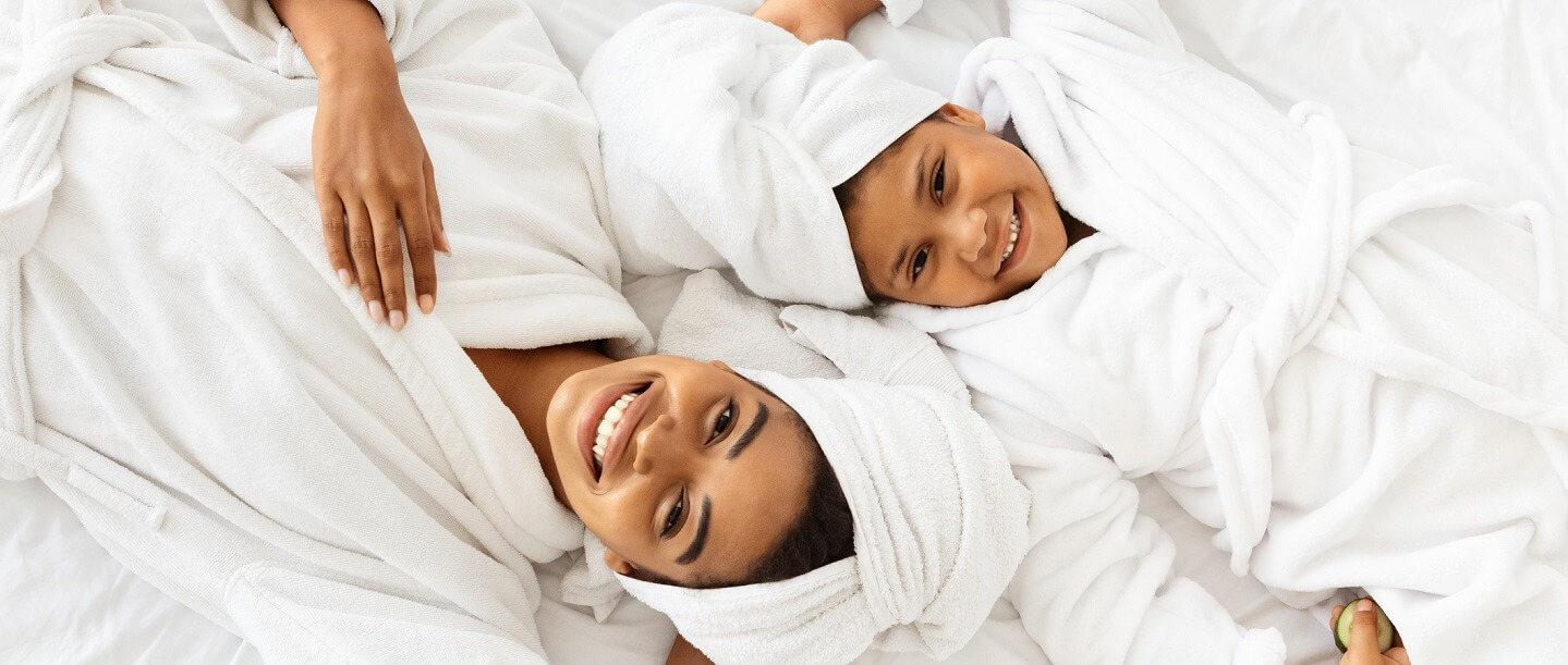 woman and child in bathrobes laying beside each other